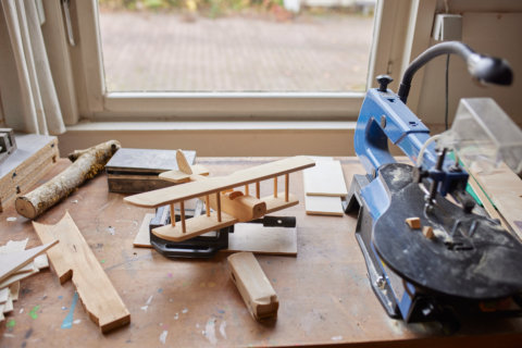 Werkstatt: ein Modellflugzeug aus Holzbau liegt auf der Werkbank