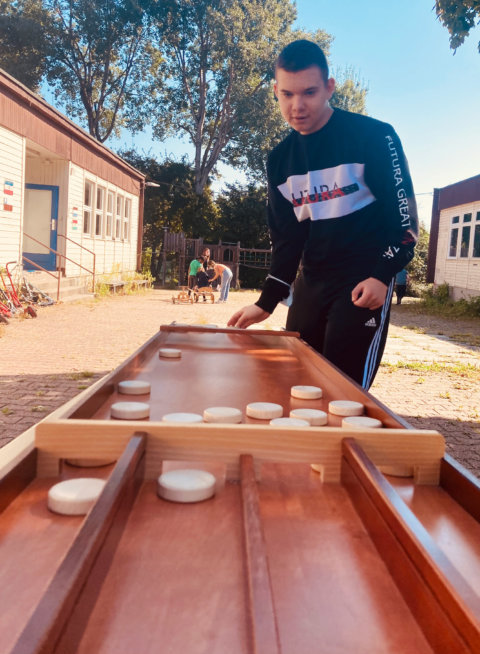 Schulhof: Schüler spielt Brettspiel aus Holz